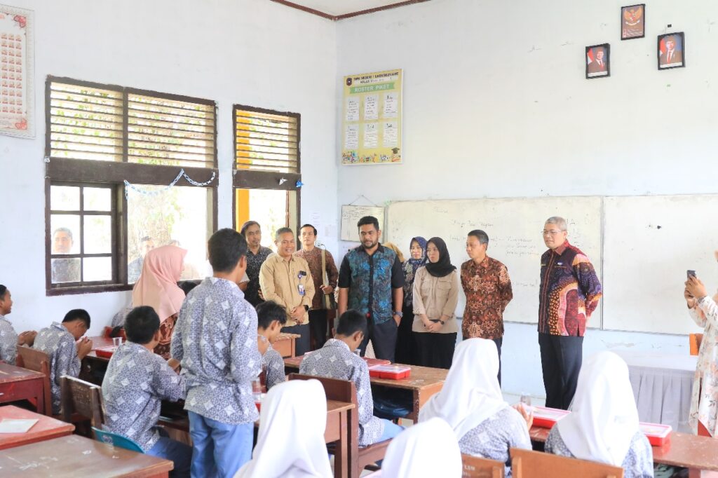 Foto: Sekdako Lhokseumawe T. Adnan, Kamis (20/2/2025), meninjau proses pembagian makanan bergizi gratis perdana di Lhokseumawe.